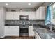 Updated kitchen with white cabinets, black backsplash, and stainless steel appliances at 900 Harbor Ave, Henderson, NV 89002