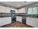 A modern kitchen with white cabinets, updated countertops, stainless steel appliances, and a window at 900 Harbor Ave, Henderson, NV 89002