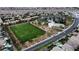Aerial view displays community park with a large grassy field, tennis court, and recreational amenities amidst homes at 9052 Pine Mission Ave, Las Vegas, NV 89143