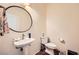 Cozy half bathroom featuring a pedestal sink and round mirror at 10798 Muscari Way, Las Vegas, NV 89141