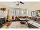 Open-concept living room featuring a stone fireplace and large windows at 10798 Muscari Way, Las Vegas, NV 89141