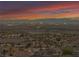 Stunning aerial view of a community with city skyline and distant mountains under a vibrant twilight sky at 1124 Whistle Ct, Henderson, NV 89011