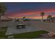 A cozy backyard featuring a modern fire pit, artificial grass, and towering palm trees against a vibrant sunset at 1124 Whistle Ct, Henderson, NV 89011