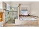 Bright bathroom showcasing separate glass-enclosed shower and a soaking tub under a window at 1124 Whistle Ct, Henderson, NV 89011