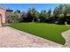 Spacious backyard featuring lush artificial grass, mature landscaping, and brick pavers at 2805 Proust Ct, Henderson, NV 89044