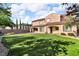 Expansive backyard featuring lush green lawn, mature trees, and covered patio area at 2805 Proust Ct, Henderson, NV 89044