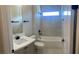 Bright bathroom features marble tiling, white vanity with black hardware, shower-tub, and a window at 2805 Proust Ct, Henderson, NV 89044