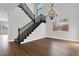 Elegant foyer with wood floors, staircase with black banister, and decorative chandelier lighting at 2805 Proust Ct, Henderson, NV 89044
