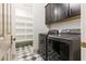 Well-equipped laundry room with modern washer, dryer, shelving, and checkerboard floors at 42 Carolina Cherry Dr, Las Vegas, NV 89141