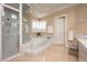 Elegant bathroom with a glass-enclosed shower, a garden tub with marble surround, and neutral tones at 5020 Spanish Heights Dr, Las Vegas, NV 89148