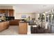 Open-concept kitchen with dark countertops, wood cabinetry, and views of the dining area and fireplace at 5020 Spanish Heights Dr, Las Vegas, NV 89148