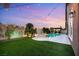 Backyard featuring refreshing pool, lush lawn, and ambient string lights for relaxed outdoor living at 5940 Vizzi Ct, Las Vegas, NV 89131