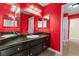Red bathroom featuring a granite-topped vanity with dark cabinets and a large mirror at 94 Fantasia Ln, Henderson, NV 89074