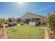 Inviting backyard featuring lush green grass, patio seating, and blooming rose bushes at 10126 Cliff Dwellings Ave, Las Vegas, NV 89178