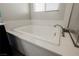 Close up of a bright white modern bathtub with faucet and white textured surround at 10126 Cliff Dwellings Ave, Las Vegas, NV 89178