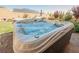 A luxurious hot tub filled with bubbling water, nestled in a backyard with plants and a blue umbrella at 10126 Cliff Dwellings Ave, Las Vegas, NV 89178