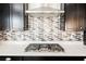 Close-up of a kitchen with stainless steel gas cooktop, modern backsplash, and dark cabinetry at 10126 Cliff Dwellings Ave, Las Vegas, NV 89178