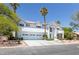 View of the front exterior featuring a three car garage and desert landscaping with mature trees at 2209 Purple Majesty Ct, Las Vegas, NV 89117