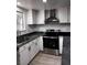 Corner view of kitchen with stainless steel oven and range hood, and white cabinets and black countertops at 3275 Arville St # C, Las Vegas, NV 89102