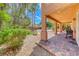 Covered patio with stone flooring overlooks the lush backyard with mature landscaping and barbecue area at 5860 Thai Coast St, Las Vegas, NV 89130