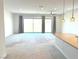 Spacious living room with neutral carpet, pendant lights, sliding glass doors, and view to the backyard at 8550 Lost Pony St, Las Vegas, NV 89148