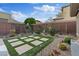 Desert landscaping with a touch of modern design, with green turf and decorative stones in the backyard at 10018 Regency Square Ave, Las Vegas, NV 89148