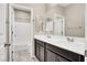 Bright bathroom features double sinks, dark cabinets, a large mirror, and a shower-tub combination at 10976 Bluebell Basin Rd, Las Vegas, NV 89179