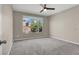 Bright and spacious bedroom with neutral carpeting, a ceiling fan, and a large window at 10976 Bluebell Basin Rd, Las Vegas, NV 89179