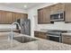 Kitchen features stainless steel refrigerator and appliances, granite counters and dark wood cabinets at 11228 Burning River St, Las Vegas, NV 89183