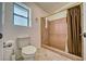 Standard bathroom featuring tiled shower and toilet with neutral colored walls and frosted window at 151 Hornet St, Pahrump, NV 89048