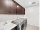 Laundry room features a utility sink, modern washer and dryer, and sleek, dark wood cabinets at 1512 Sagefield Way, Logandale, NV 89021