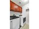 Cherry wood cabinets above modern, front loading washer and dryer at 41 Stablewood Ct, North Las Vegas, NV 89084