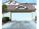 Attached home featuring a white garage door, desert landscaping and red tile roof at 855 N Stephanie St # 112, Henderson, NV 89014