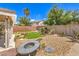 Backyard featuring desert landscaping, rock, synthetic grass and fire pit area at 3728 Ashling St, Las Vegas, NV 89129