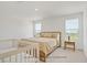 Bright bedroom featuring a wooden bed frame, neutral bedding, and a charming crib at 5692 Tinar St, Las Vegas, NV 89113