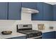 Modern kitchen featuring blue cabinets, stainless steel appliances, and marble countertops at 5692 Tinar St, Las Vegas, NV 89113