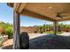 Covered patio featuring a ceiling fan, lush landscaping, block wall and desert views at 1128 Via Della Curia, Henderson, NV 89011