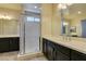 Bright bathroom featuring double vanity, framed mirrors, dark cabinets, and glass-enclosed shower at 1128 Via Della Curia, Henderson, NV 89011