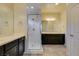 Bright bathroom featuring double vanity, framed mirrors, dark cabinets, and glass-enclosed shower at 1128 Via Della Curia, Henderson, NV 89011