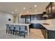Modern kitchen with a large island, bar seating, stainless steel appliances, and dark cabinets at 1128 Via Della Curia, Henderson, NV 89011