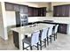 Modern kitchen featuring a large island, stainless steel appliances, and dark cabinetry at 1128 Via Della Curia, Henderson, NV 89011