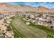 Aerial view displays rolling green fairways and sand traps of the golf course surrounded by mountains and luxury homes at 11534 Glowing Sunset Ln, Las Vegas, NV 89135