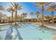 Beautiful community pool featuring lush palm trees, shaded seating areas, and sparkling water for serene relaxation at 11534 Glowing Sunset Ln, Las Vegas, NV 89135