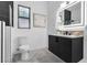 This bathroom features an illuminated mirror, black cabinets, white walls, and elegant gray marble flooring at 1350 Rossini St, Henderson, NV 89052