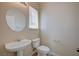 Compact half-bathroom featuring a pedestal sink, toilet, and a round mirror, maximizing space with practical design elements at 1531 Evening Spirit Ave, Las Vegas, NV 89183