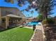 Backyard featuring a pool, covered patio, artificial grass, and palm trees at 2065 Pinion Springs Dr, Henderson, NV 89074
