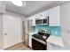 Updated kitchen showcasing modern stainless steel appliances, white cabinets, and eye-catching teal backsplash at 211 Mission Laguna Ln # 205, Las Vegas, NV 89107
