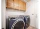 This laundry room includes modern washer/dryer units and wooden cabinets at 220 Hollyfern St, Henderson, NV 89074