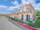 Stylish townhouse with arched entryway, lush landscaping, and a community street view at 24 Via Vasari # 104, Henderson, NV 89011