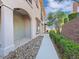 Townhouse exterior featuring a paved walkway, stone landscaping, and arched architectural details at 24 Via Vasari # 104, Henderson, NV 89011